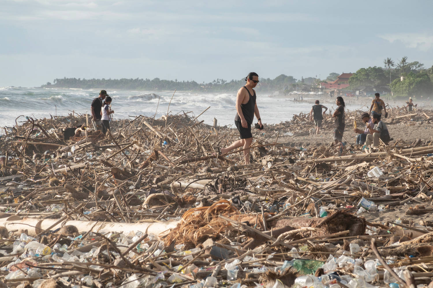Чуждестранни туристи се разхождат по отрупания с отпадъци плаж на